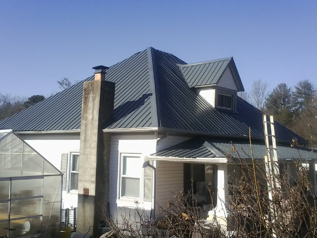 Dark blue standing seam metal roof on a white farmhouse with dormer — Slate & Tile Roof Repair by Roofing Brothers in Bechtelsville