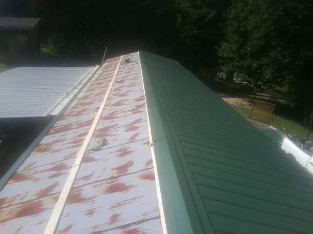 Old rusted panels beside newly installed green metal roofing — Wind Damage Roof Repair by Roofing Brothers in Bechtelsville