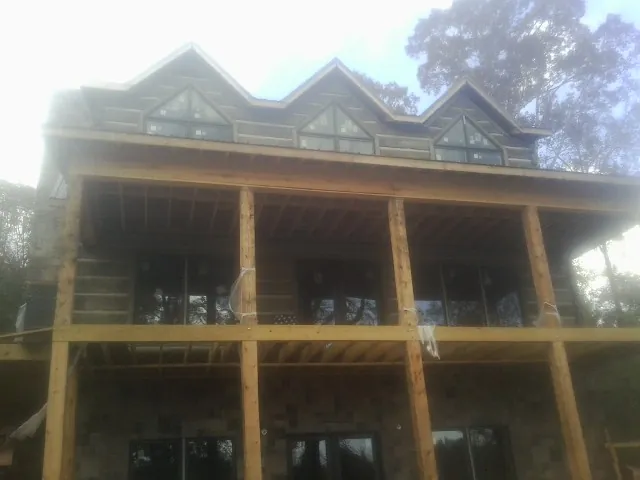 Dormers and porch framing on a large log home under construction — Roof Coating work by our crew in Bechtelsville