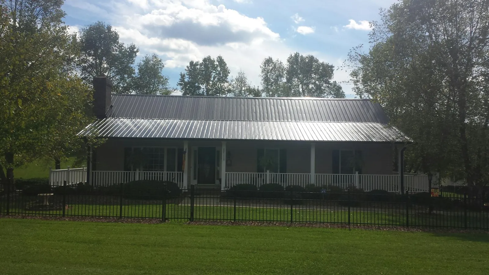 Gray metal roof on a brick ranch with a full width front porch — Gutter Guard Installation work by our crew in Bechtelsville
