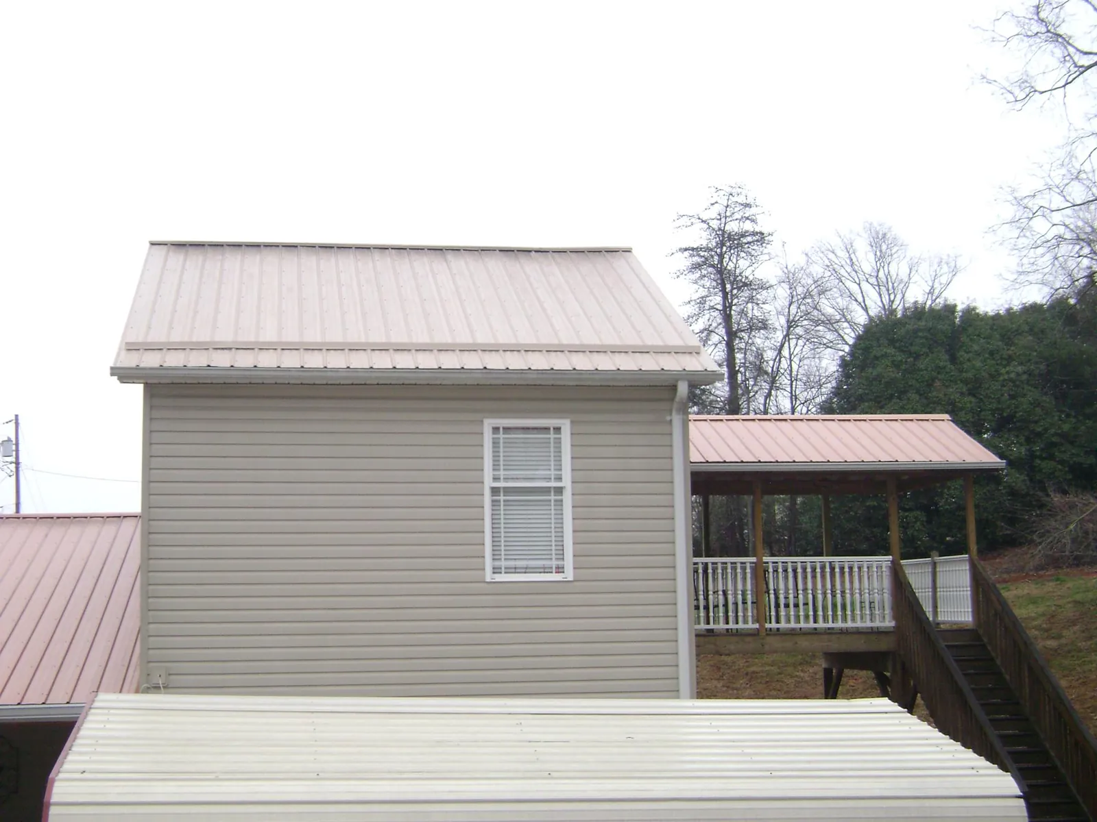 Tan metal roofs on a two story addition and attached porch, from a Roof Replacement job in Bechtelsville