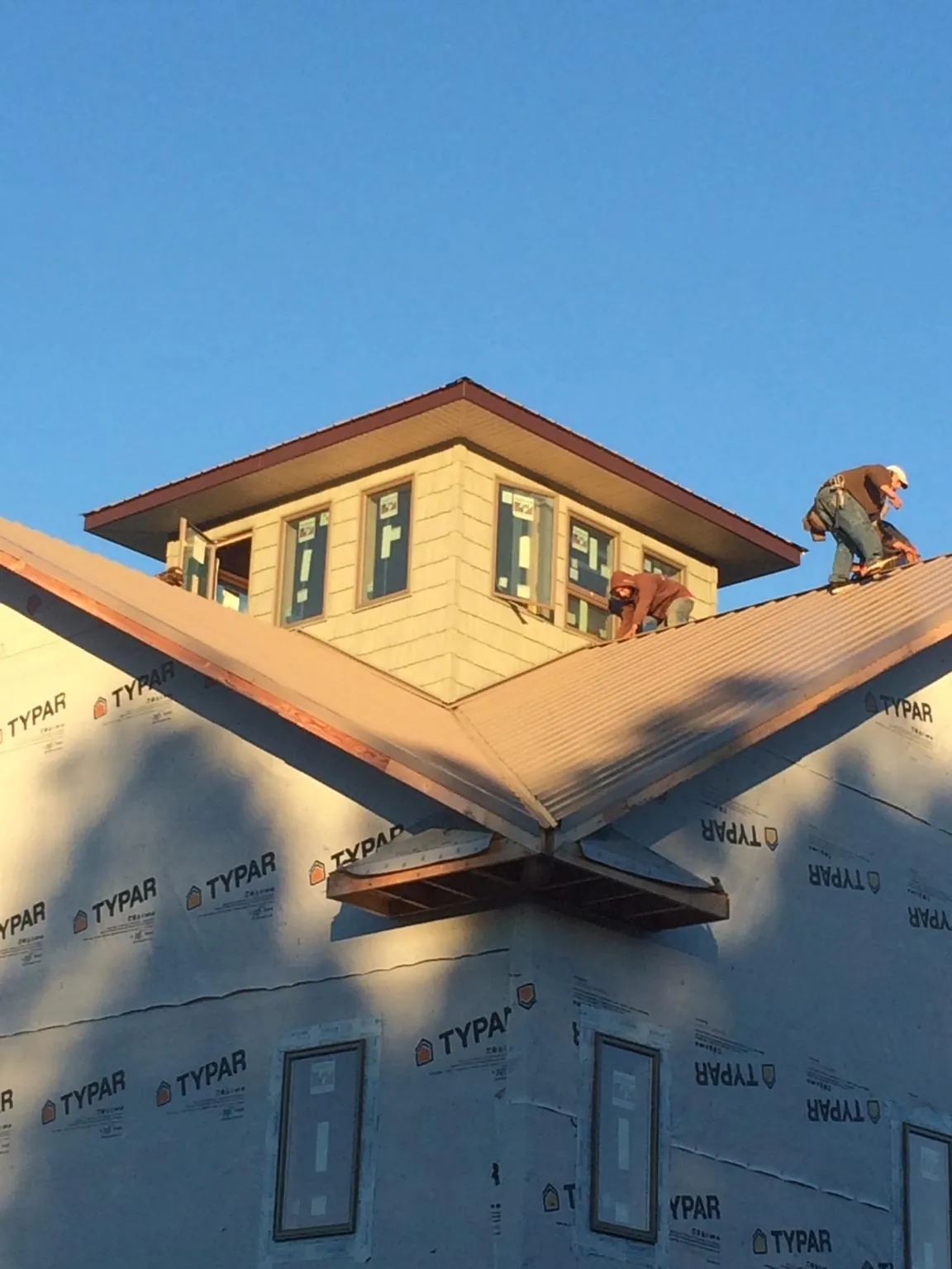 Roofers working around a rooftop cupola on a new metal roof at sunset — Roof Waterproofing in Bechtelsville by Roofing Brothers